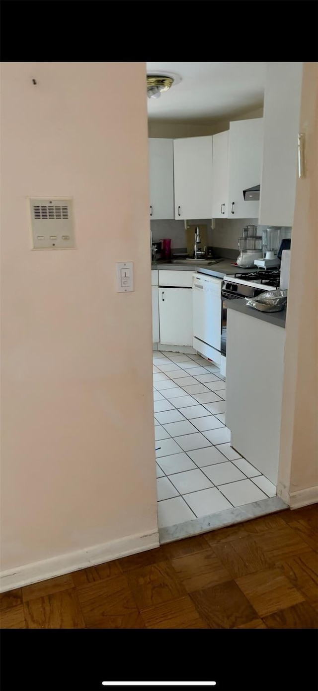 10 Ipswich Ave Unit 4M, Great Neck, NY 11021 - kitchen featuring white appliances, white cabinets, dark countertops, a sink, and baseboards