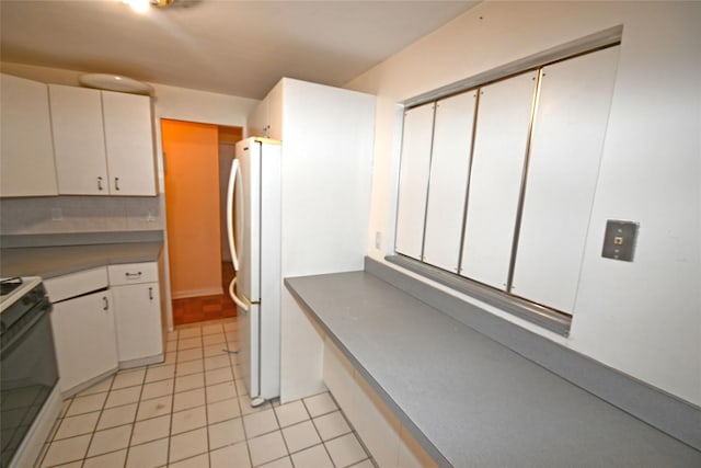 10 Ipswich Ave Unit 4M, Great Neck, NY 11021 - kitchen featuring stove, freestanding refrigerator, light tile patterned floors, and white cabinetry