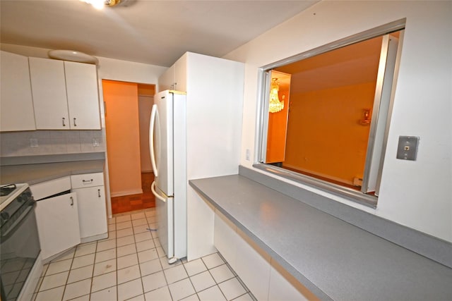 10 Ipswich Ave Unit 4M, Great Neck, NY 11021 - kitchen with stove, light tile patterned floors, white cabinetry, and freestanding refrigerator