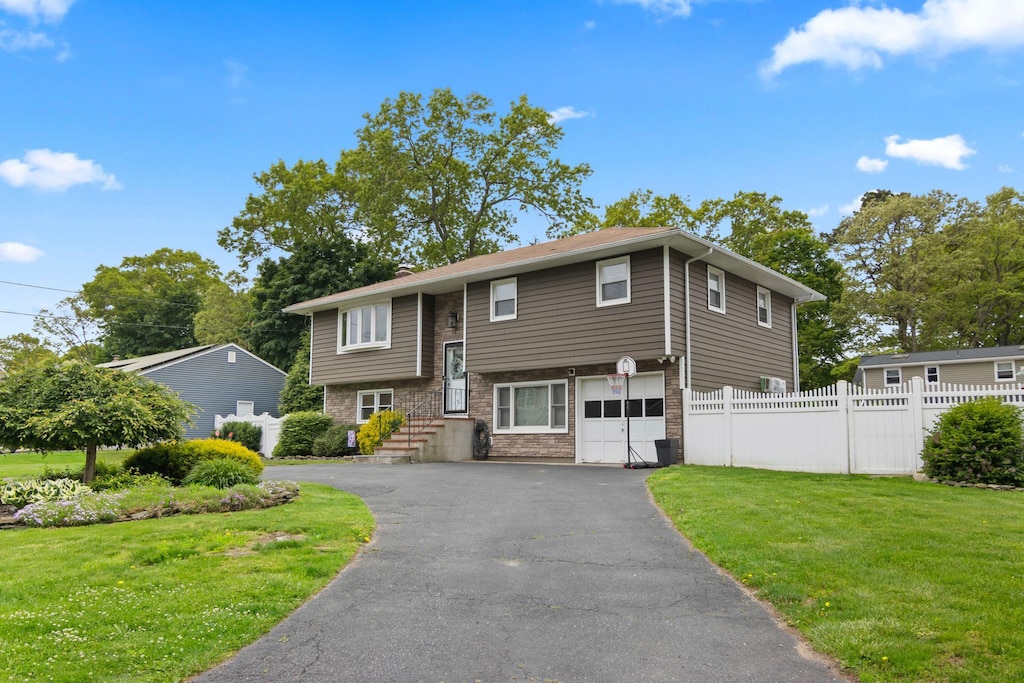 176 Harrison Ave, Miller Place, NY 11764 - raised ranch featuring asphalt driveway, a garage, and stone siding
