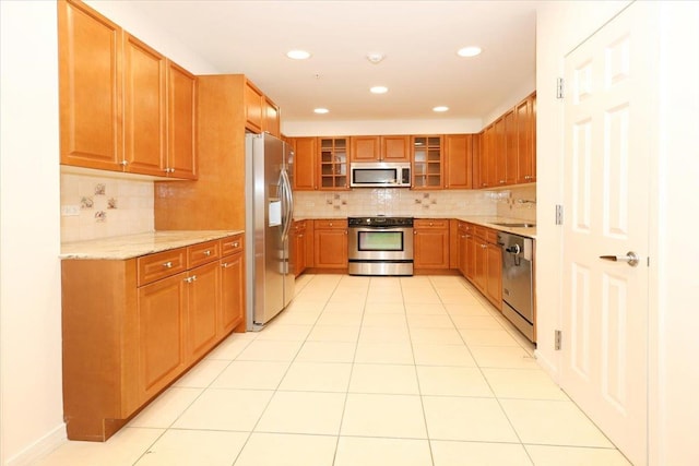 100 Harbor View Dr SW Unit 335, Port Washington, NY 11050 - kitchen featuring stainless steel appliances, decorative backsplash, a sink, glass insert cabinets, and light stone counters