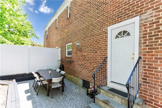 view of patio with entry steps, fence, and outdoor dining area