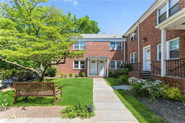 townhome / multi-family property with brick siding and a front lawn