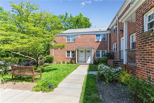view of property featuring brick siding and a front lawn