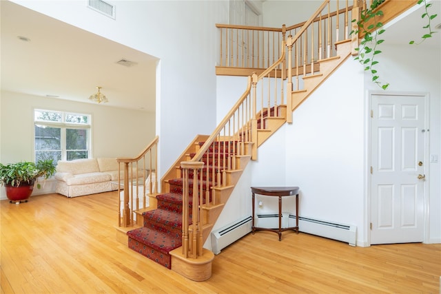 9 Golf Course Dr, Suffern, NY 10901 - staircase featuring wood finished floors, a towering ceiling, and a baseboard radiator