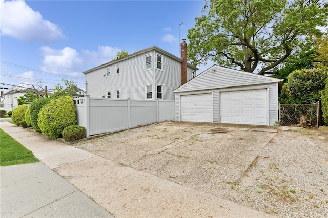 view of home's exterior featuring fence, an outbuilding, a garage, and a chimney