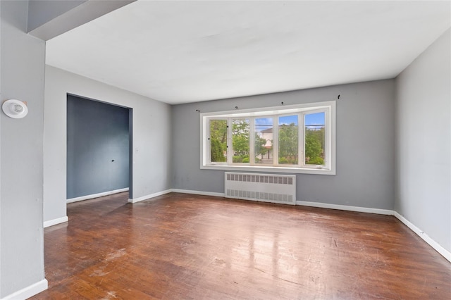 spare room featuring radiator heating unit, wood finished floors, and baseboards