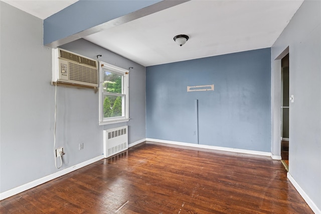 spare room featuring radiator heating unit, baseboards, wood finished floors, and a wall mounted AC