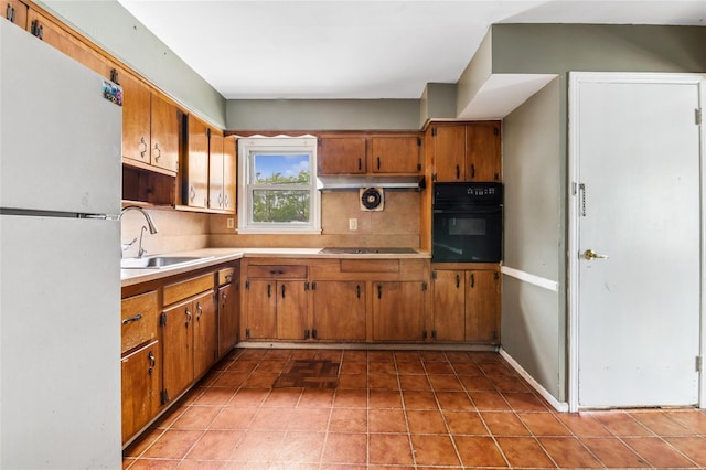 kitchen with black appliances, a sink, tasteful backsplash, and brown cabinetry