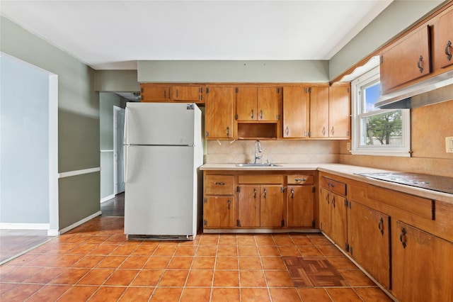 kitchen with freestanding refrigerator, a sink, decorative backsplash, electric stovetop, and light countertops
