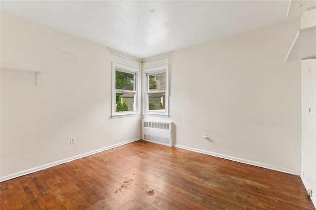 spare room featuring radiator, hardwood / wood-style flooring, and baseboards