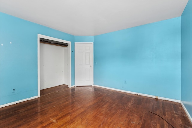unfurnished bedroom featuring wood finished floors, baseboards, and a closet