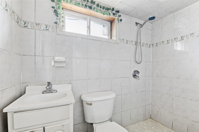 bathroom with a tile shower, vanity, and toilet