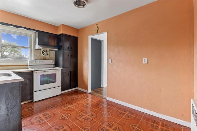 kitchen with electric stove, baseboards, light countertops, tile patterned floors, and backsplash