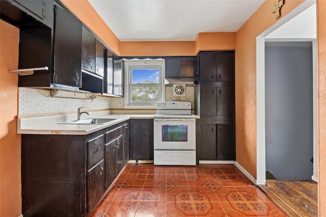 kitchen featuring white electric stove, a sink, dark tile patterned flooring, tasteful backsplash, and light countertops