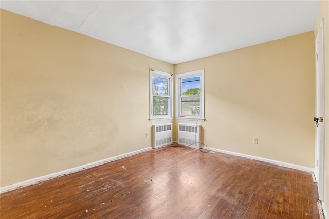 spare room with radiator, baseboards, and wood-type flooring