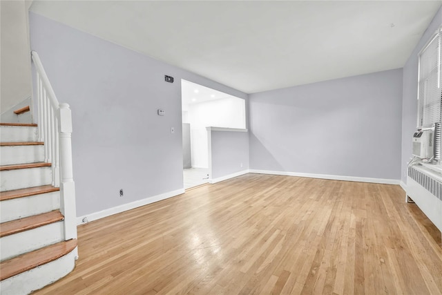 1141 E 213th St, Bronx, NY 10469 - unfurnished living room with stairs, light wood-type flooring, baseboards, and radiator heating unit