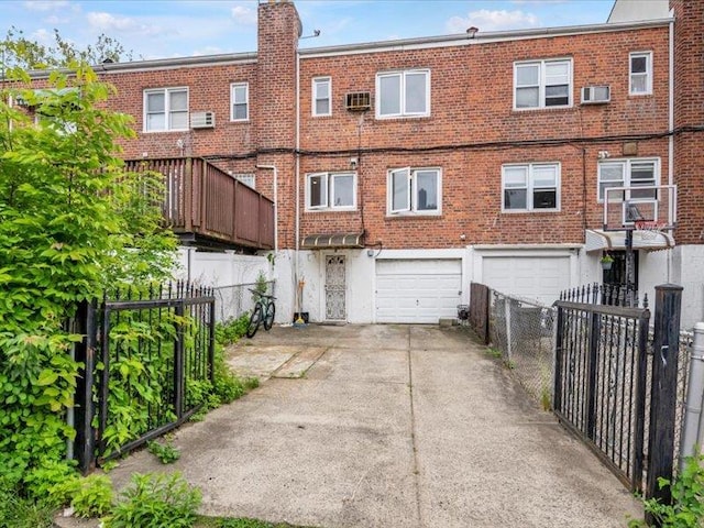 150-31 78th Ave, Flushing, NY 11367 - back of property featuring a garage, concrete driveway, a wall unit AC, fence, and brick siding
