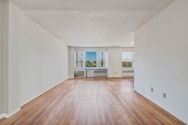 190 W Merrick Rd Unit 4E, Freeport, NY 11520 - unfurnished living room featuring radiator, wood finished floors, and an AC wall unit