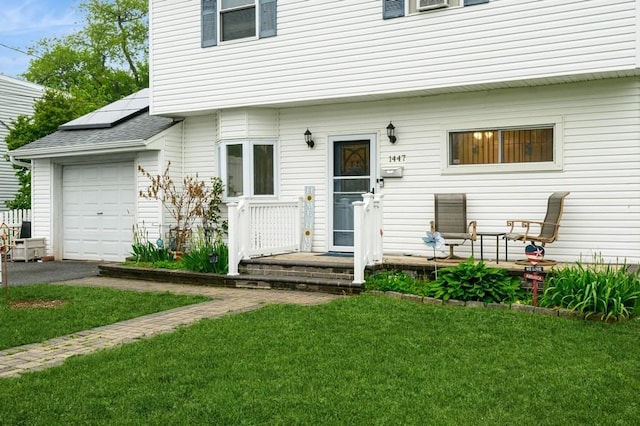 back of house with solar panels, a yard, an attached garage, and driveway