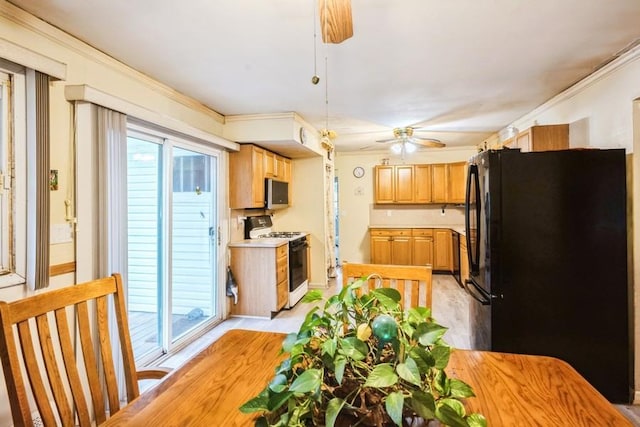 kitchen featuring gas range, freestanding refrigerator, stainless steel microwave, a ceiling fan, and crown molding