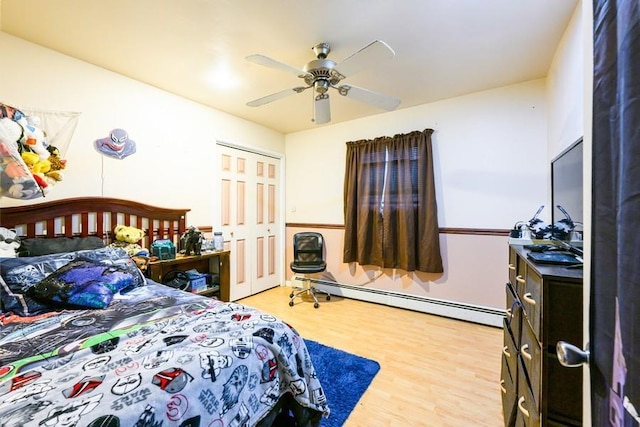 bedroom featuring baseboard heating, wood finished floors, a closet, and ceiling fan