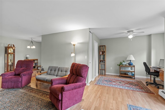 living room featuring wood finished floors, a chandelier, ceiling fan, an office area, and baseboards