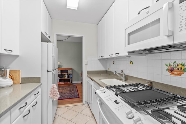 kitchen featuring white appliances, a sink, white cabinets, and light tile patterned floors