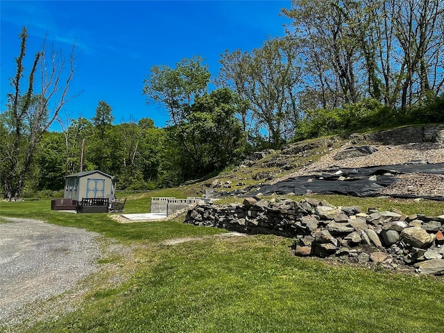 view of green lawn featuring a storage unit and an outbuilding
