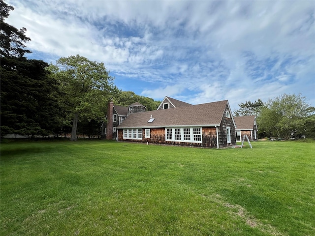 rear view of property with a yard and a shingled roof