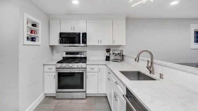 19 Barstow Rd Unit G, Great Neck, NY 11021 - kitchen with stainless steel appliances, a sink, backsplash, light stone counters, and white cabinetry