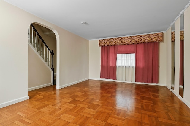 unfurnished room featuring baseboards, arched walkways, and stairway