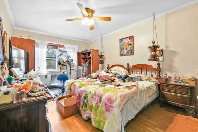 bedroom with hardwood / wood-style floors, ornamental molding, and a ceiling fan