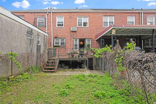back of house with brick siding, a wooden deck, and a wall mounted air conditioner