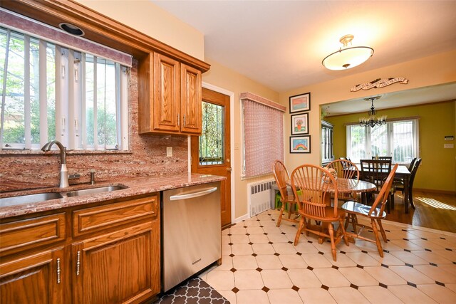 kitchen with dishwasher, a sink, brown cabinetry, light stone countertops, and light flooring