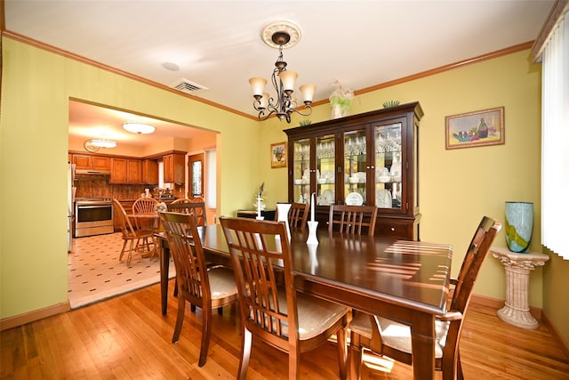 dining room featuring a chandelier, light wood-style flooring, ornamental molding, and baseboards