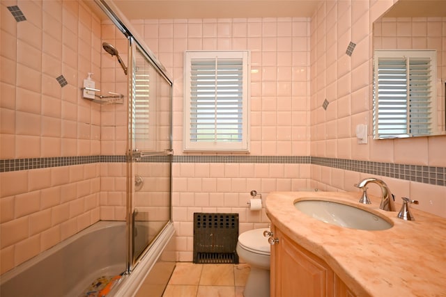full bath featuring radiator heating unit, tile walls, combined bath / shower with glass door, tile patterned flooring, and toilet