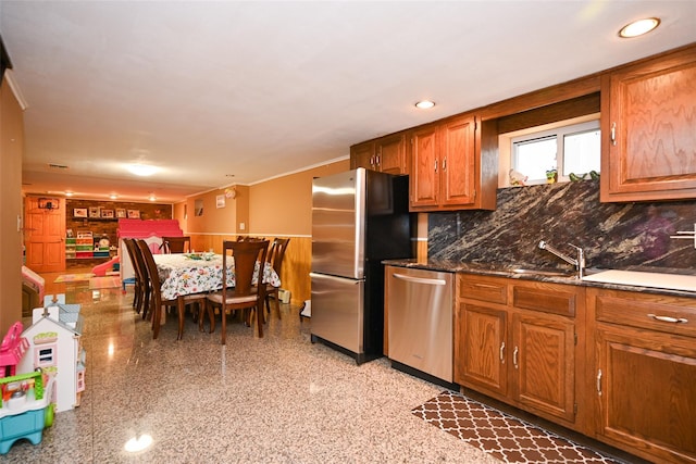 kitchen featuring stainless steel appliances, brown cabinets, backsplash, a sink, and recessed lighting