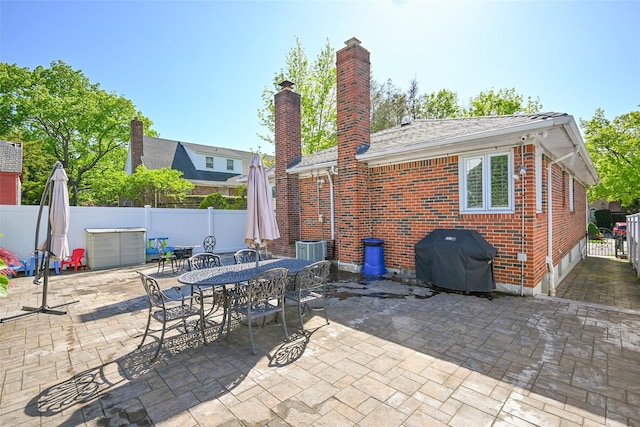 view of patio with area for grilling, a fenced backyard, outdoor dining space, and central AC unit