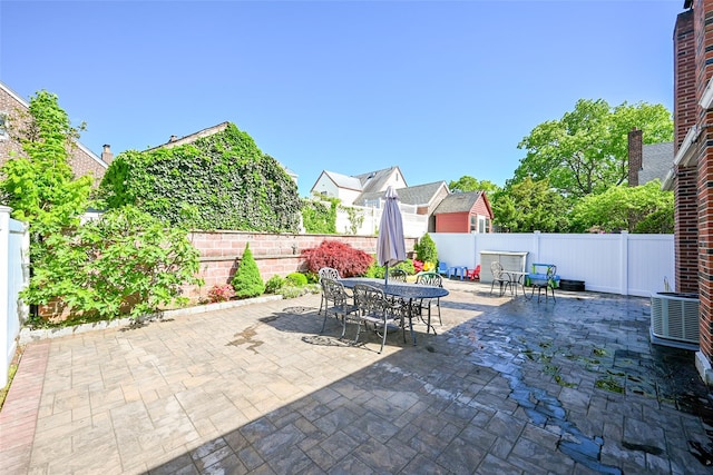 view of patio featuring outdoor dining space, a fenced backyard, and central air condition unit