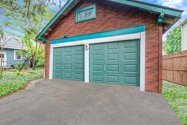 garage featuring driveway and fence
