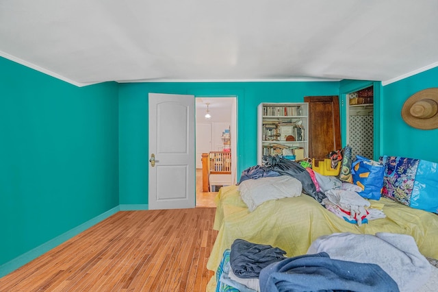 bedroom featuring ornamental molding, wood finished floors, and baseboards