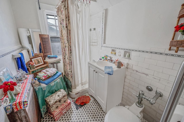 bathroom featuring tile walls, vanity, a shower with curtain, wainscoting, and toilet