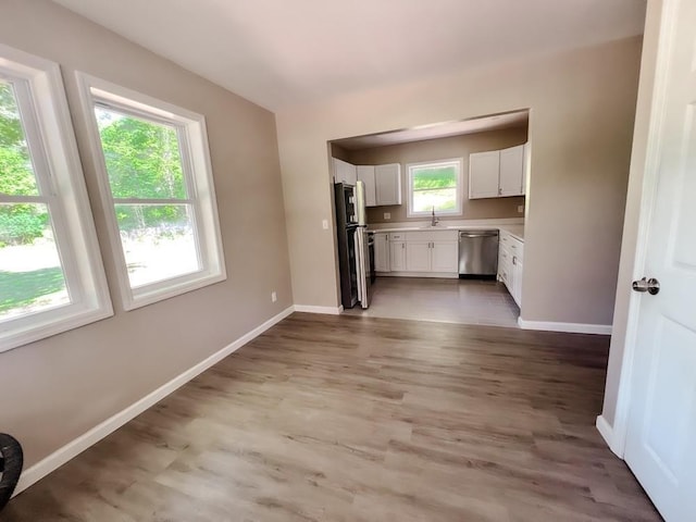 936 State Route 55a, Neversink, NY 12458 - kitchen with stainless steel dishwasher, freestanding refrigerator, a sink, light countertops, and white cabinetry