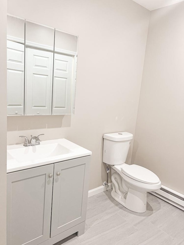 936 State Route 55a, Neversink, NY 12458 - half bathroom with baseboards, toilet, vanity, a baseboard radiator, and wood finished floors