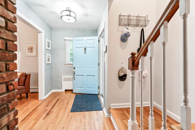 foyer entrance with radiator, stairway, a baseboard heating unit, baseboards, and light wood-style floors