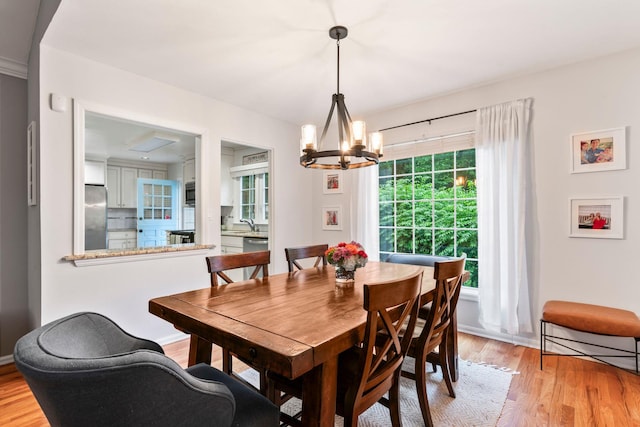 dining space with a chandelier, light wood finished floors, and baseboards