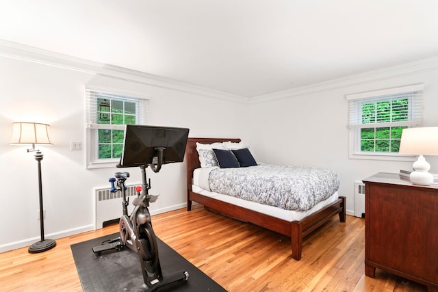 bedroom featuring radiator, light wood-style floors, ornamental molding, and baseboards