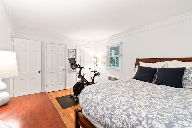 bedroom with radiator heating unit, wood finished floors, and crown molding