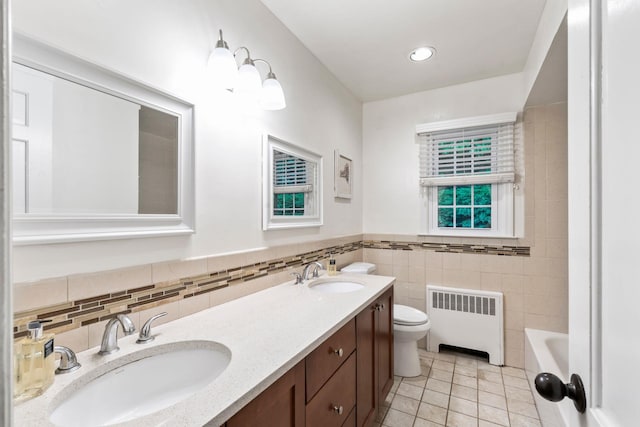 bathroom with radiator, tile walls, toilet, tile patterned floors, and double vanity